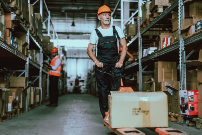 Warehouse Man in Hardhat using Forklift Cart